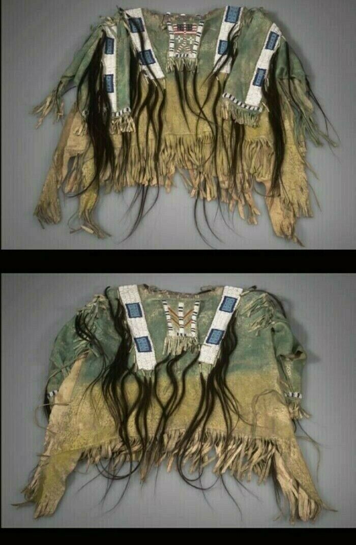 Traditional Native American garment with fringes and beadwork on a gray background