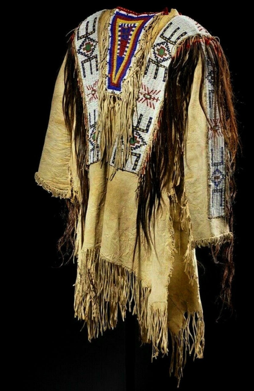 Traditional Native American garment with intricate beadwork and fringes on a black background