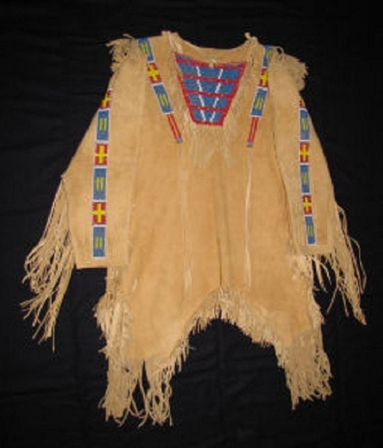 Traditional Native American garment with fringes and beadwork on a black background