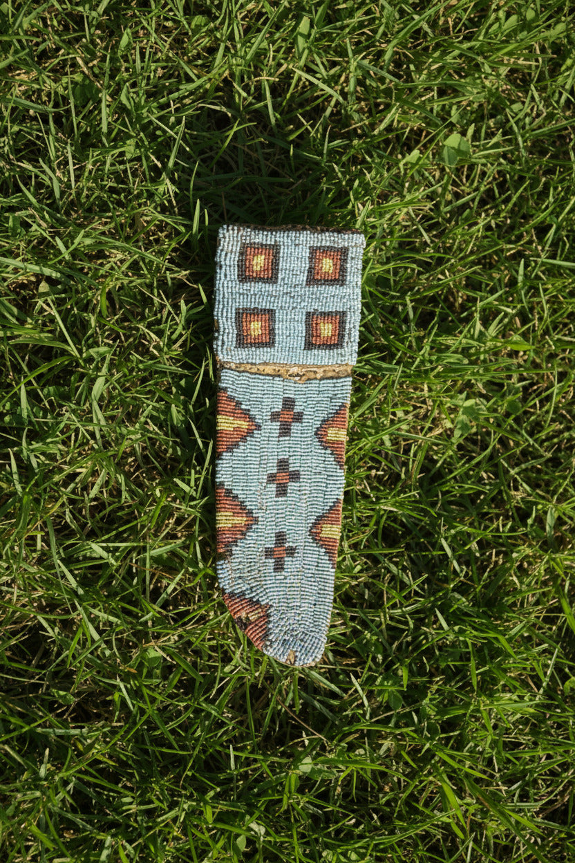 Decorative beaded knife sheath with geometric pattern on a white background