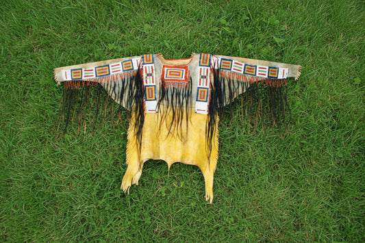 Traditional Native American War Shirt with fringes and bead work on a Grassy background
