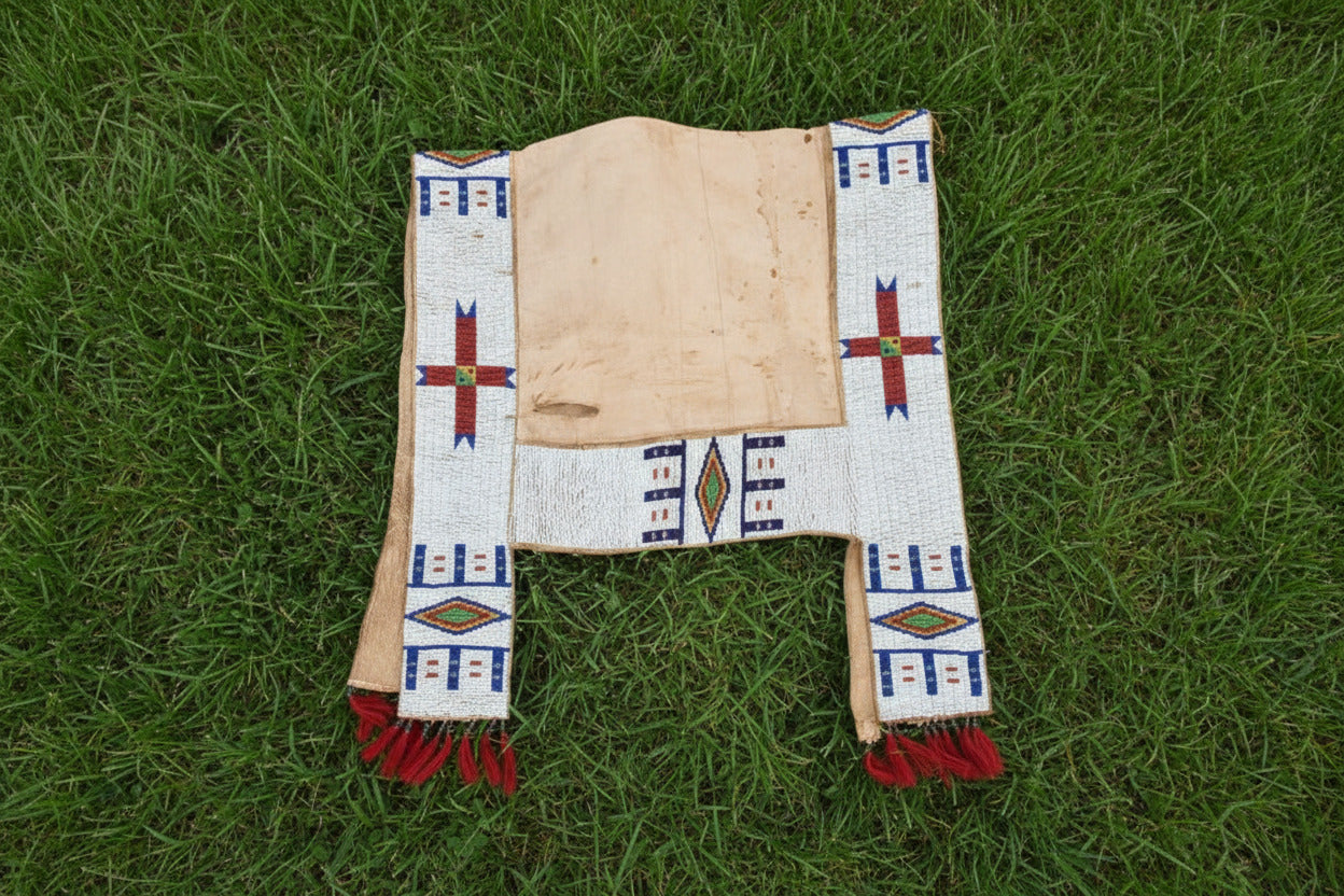 Decorative saddle blanket with geometric patterns and red fringes on a white background