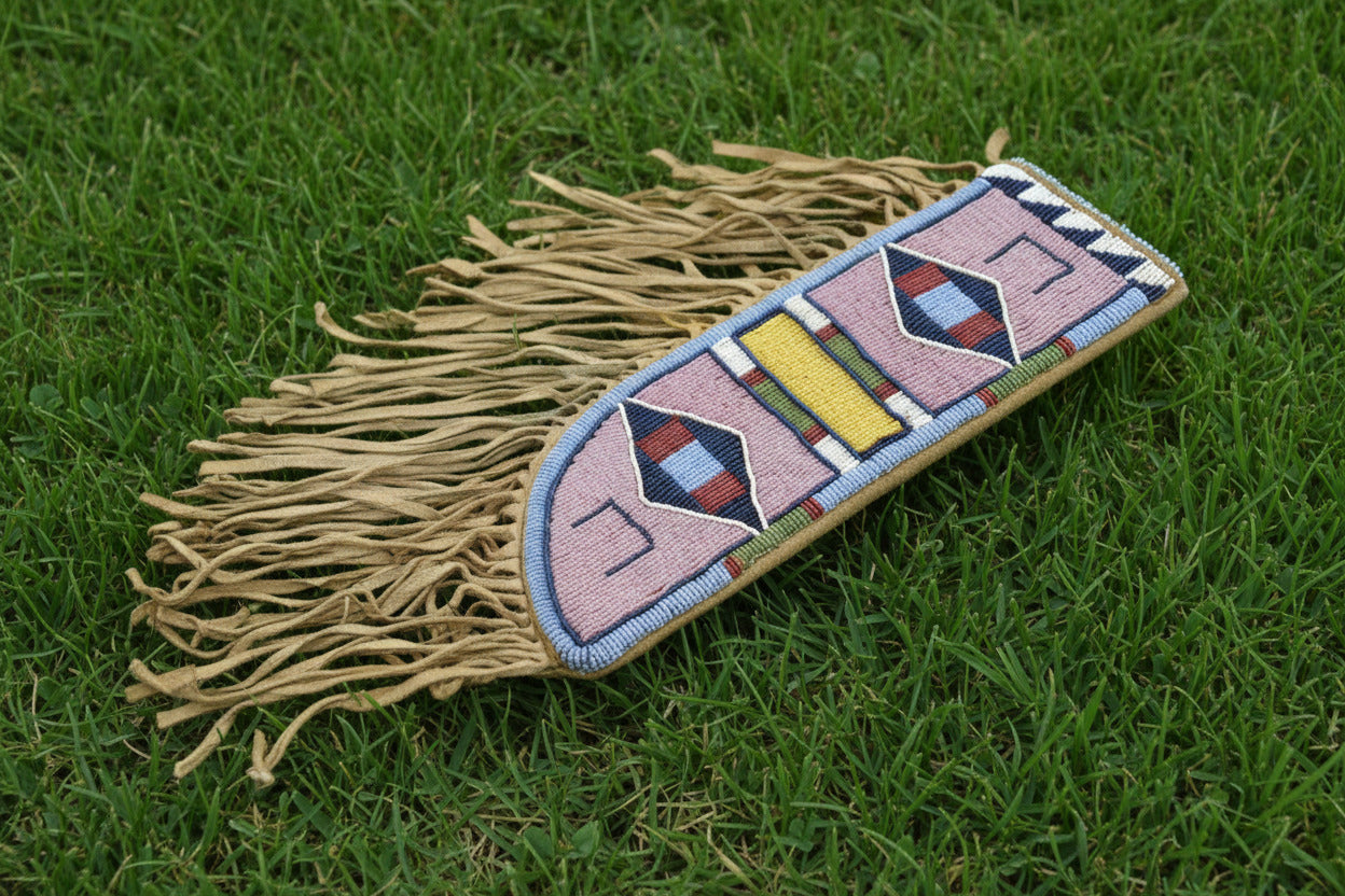 Decorative knife sheath with beadwork and fringes on a gray background