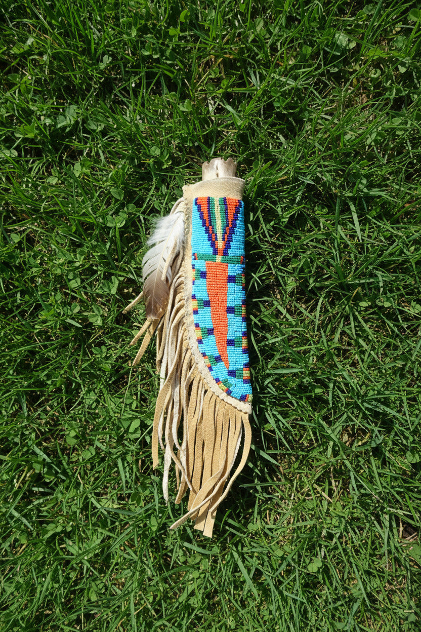 Decorative knife sheath with beadwork and fringes on a beige background