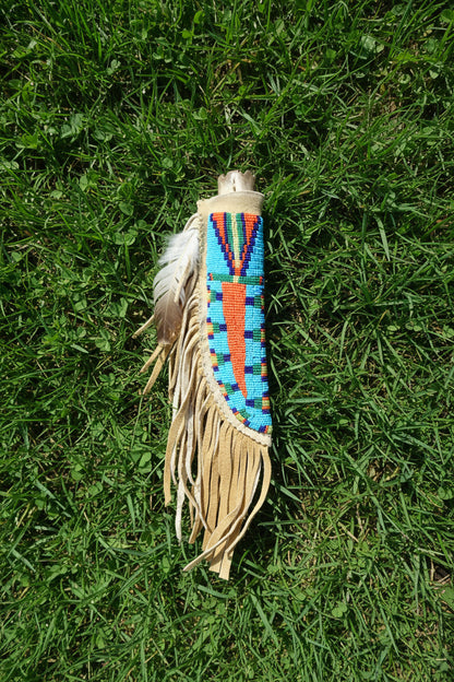 Decorative knife sheath with beadwork and fringes on a beige background