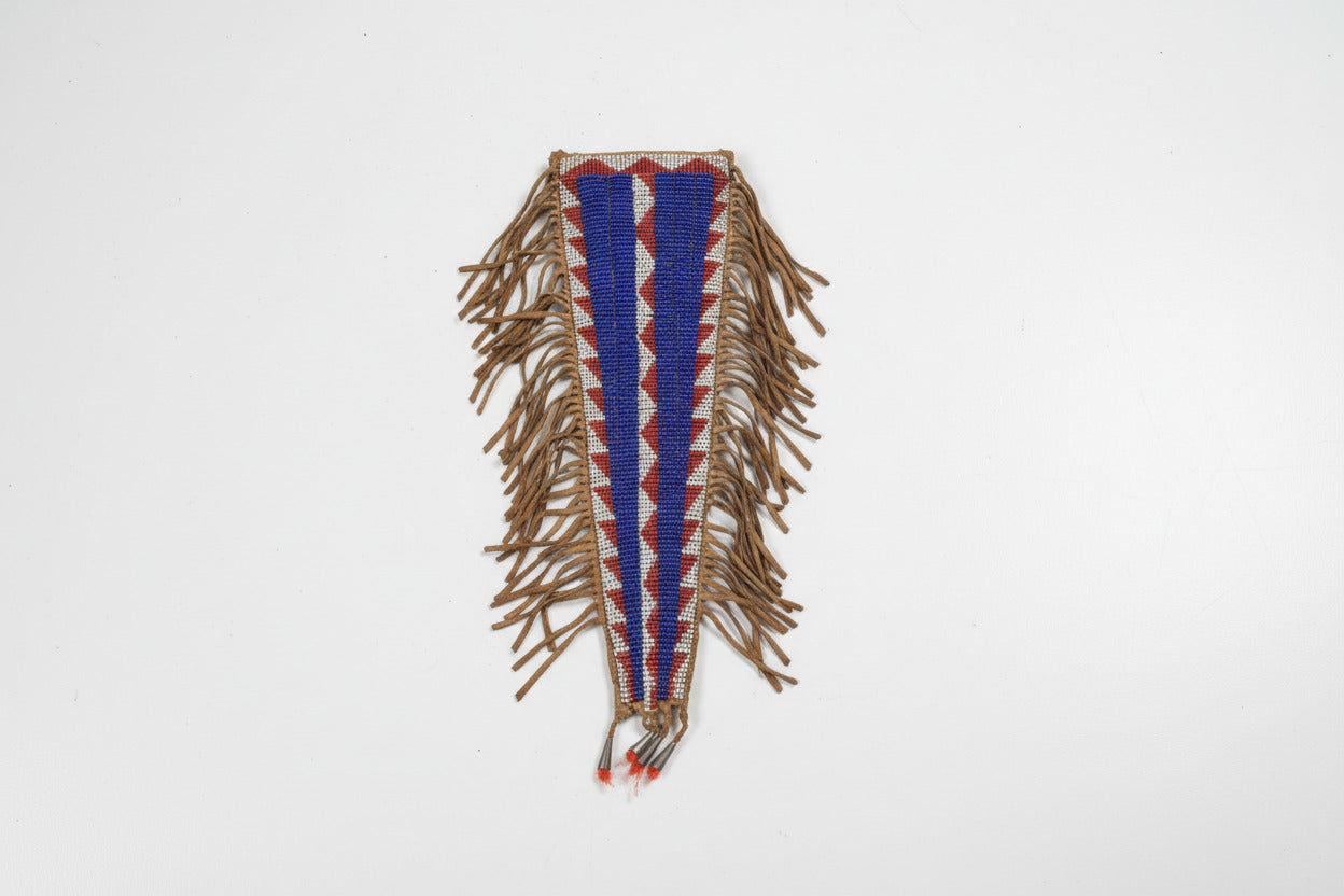 Decorative beaded knife sheath with fringes on a gray background