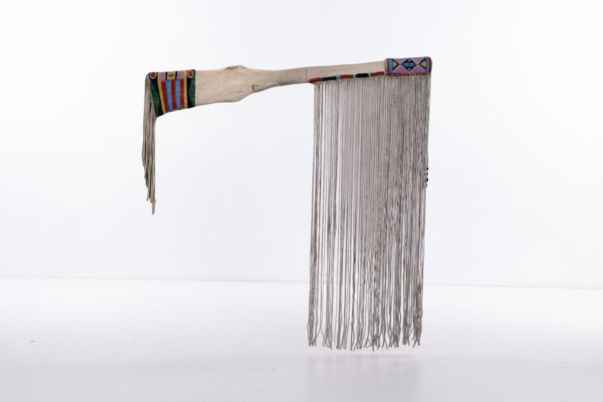 Traditional Native American rifle sheath with beads and feathers on a white background