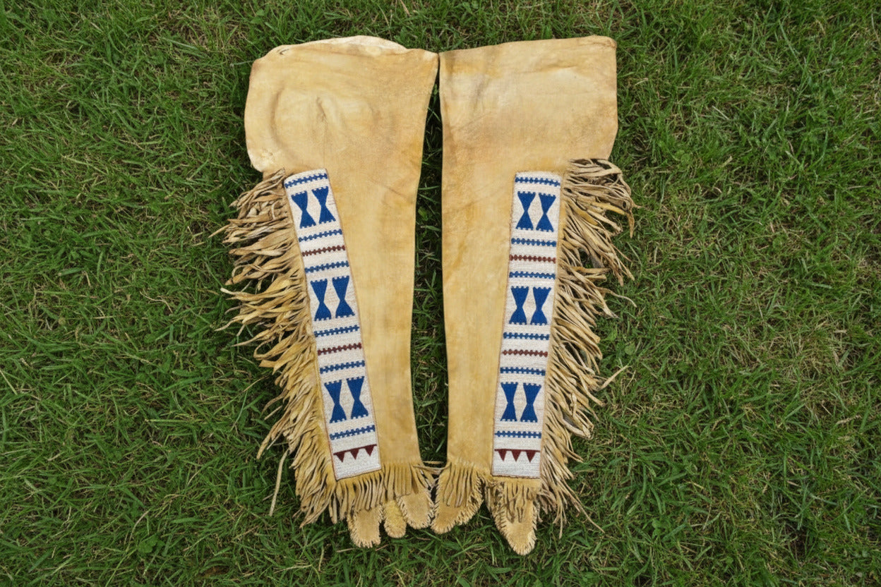 Pair of beige leather leggings with decorative blue and red patterns on a white background