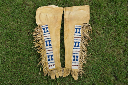 Pair of beige leather leggings with decorative blue and red patterns on a white background