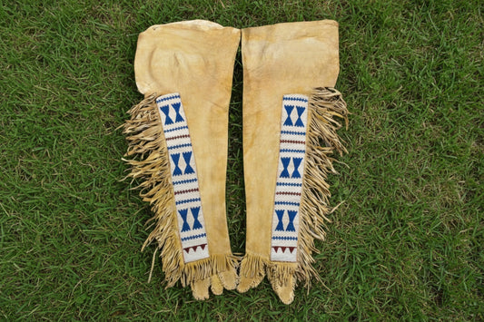 Pair of beige leather leggings with decorative blue and red patterns on a white background