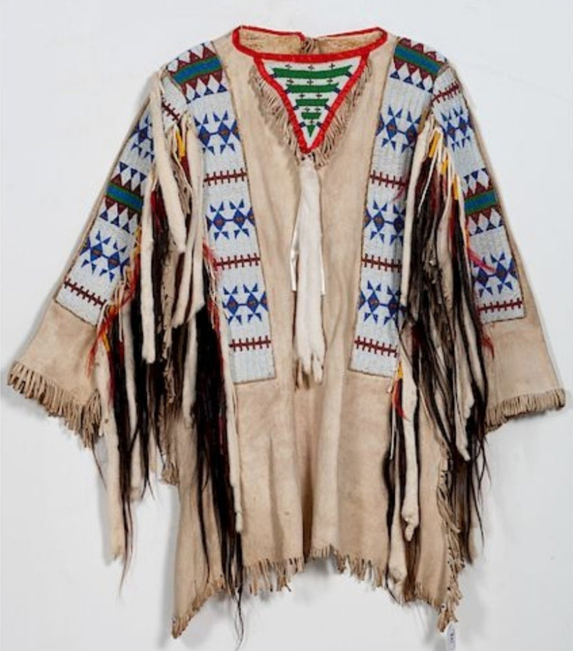 Traditional Native American garment with intricate patterns and fringes on a white background