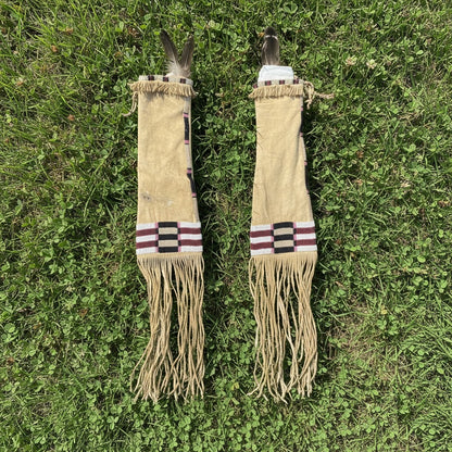 Two decorative Pipe Bag with fringes and feathers on a grassy background
