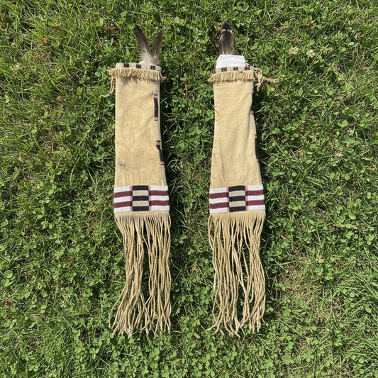 Two decorative Pipe Bag with fringes and feathers on a grassy background
