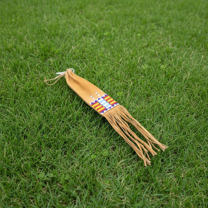 Decorative Pipe Bag with fringes and a colorful pattern on grass