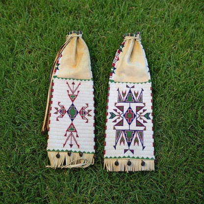 Two decorative pipe bags with geometric patterns on a grass background