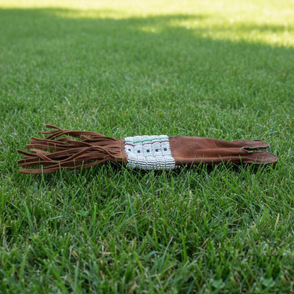 Brown leather Pipe Bag with decorative band on grass