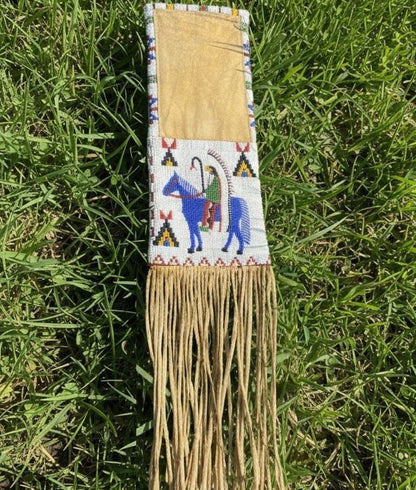 Decorative pipe bag with beadwork and fringes on a grass background