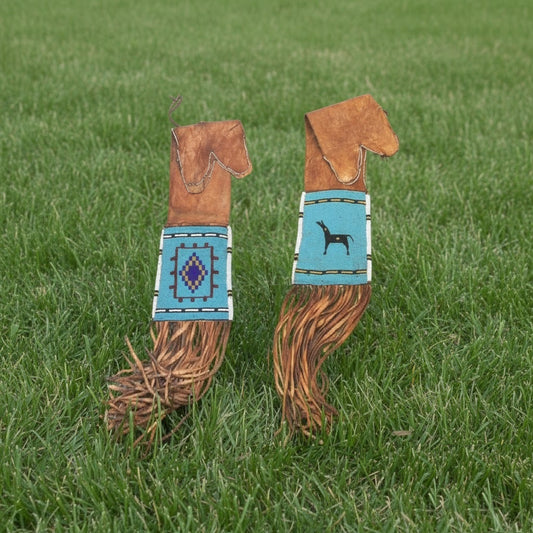 Two decorative horse pipe bag with patterned handles on a grassy background