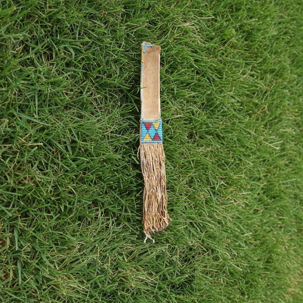 Traditional Native American tomahawk sheath with decorative pattern on grass