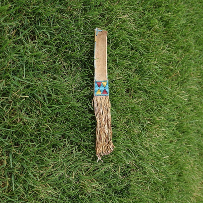 Traditional Native American tomahawk sheath with decorative pattern on grass