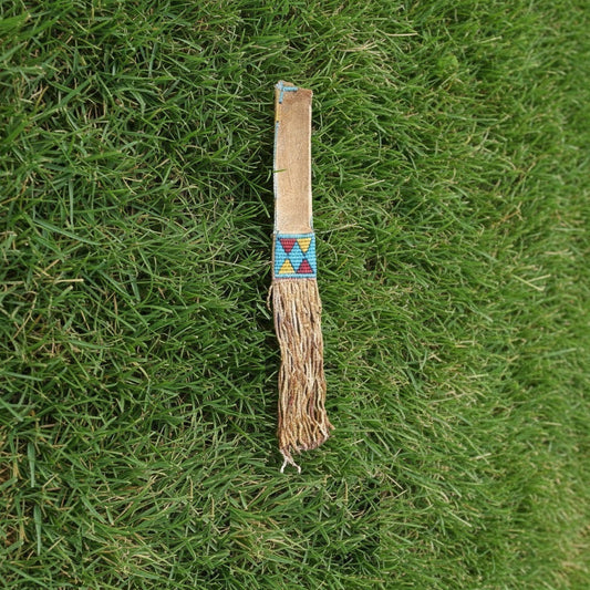 Traditional Native American tomahawk sheath with decorative pattern on grass