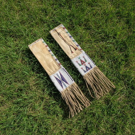 Two decorative pipe bags with patterned handles on a grassy background