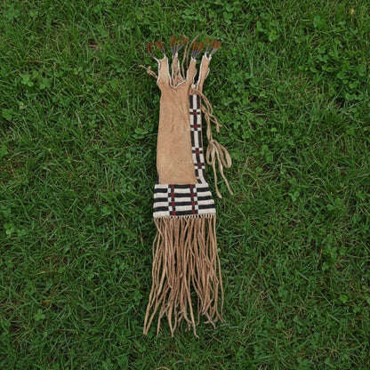 Decorative tribal pipe bag with fringes on a grassy background