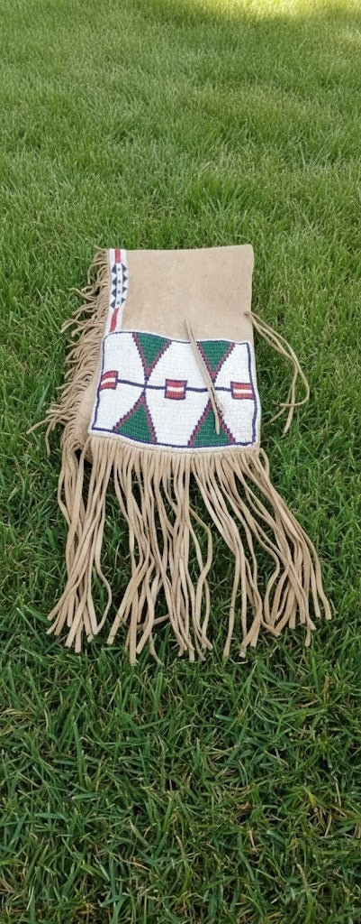 Beige bag with decorative pattern and fringes on a grassy background
