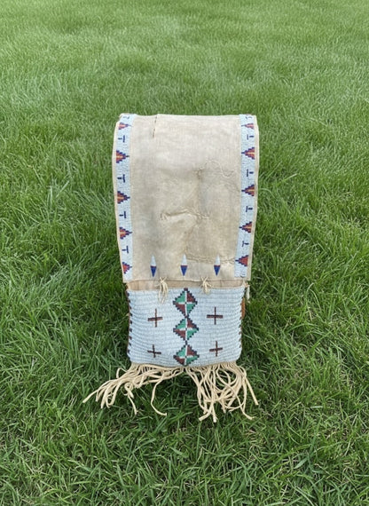 Traditional Native American saddle bag with geometric patterns on grass