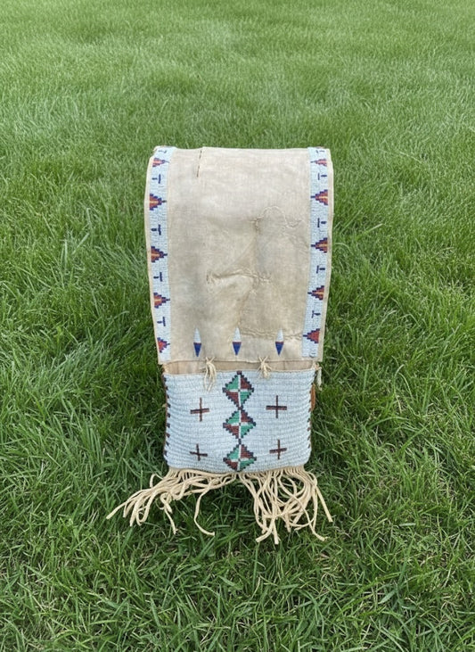 Traditional Native American saddle bag with geometric patterns on grass