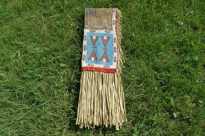 Decorative saddle bag with geometric pattern and fringes on a gray background