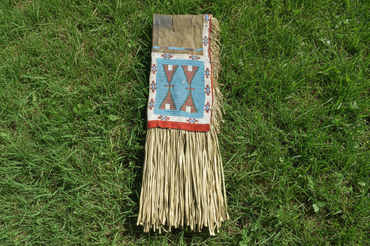 Decorative saddle bag with geometric pattern and fringes on a gray background