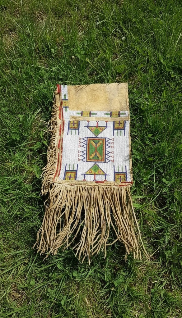 Handmade bag with geometric patterns and fringes on grass