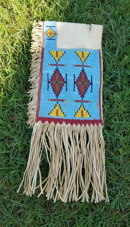 Handmade bag with geometric patterns and fringes on a grass background