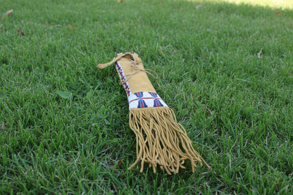 Traditional Native American pipe bag with a yellow top section and braided bottom on a white background