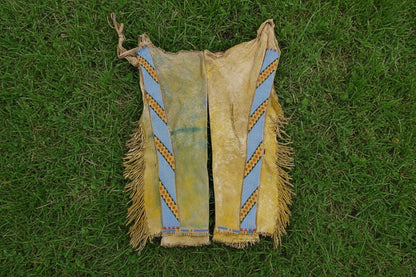 Traditional Native American leather vest with fringes and blue and brown pattern on a white background