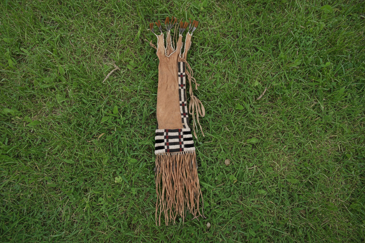 Traditional Native American pipe bag with braided hair and fringes on a white background