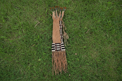 Traditional Native American pipe bag with braided hair and fringes on a white background