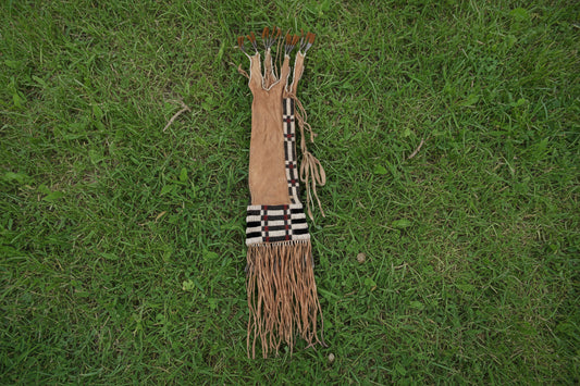 Traditional Native American pipe bag with braided hair and fringes on a white background