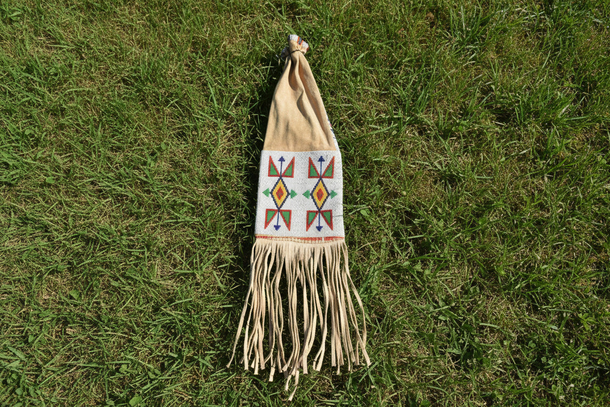 Decorative pipe bag with geometric patterns and fringes on a white background