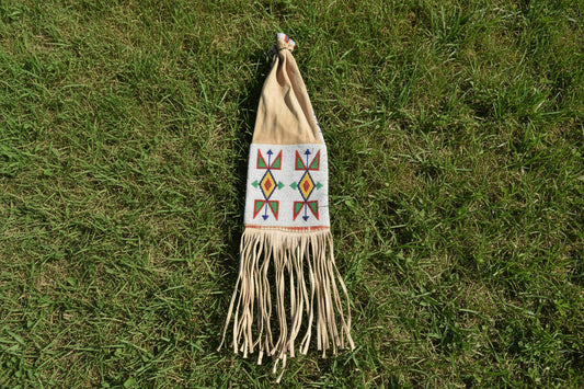 Decorative pipe bag with geometric patterns and fringes on a white background